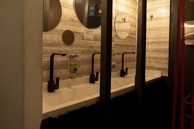 The shared washbasin counter with three black taps and round mirrors