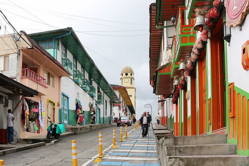Calle 5 in Salento: painted balconies in red, green and blue and the church tower at the end of the street