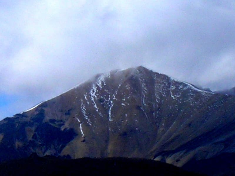 The dark summit of the Paramillo del Quindío streaked with snow under a blue-grey sky