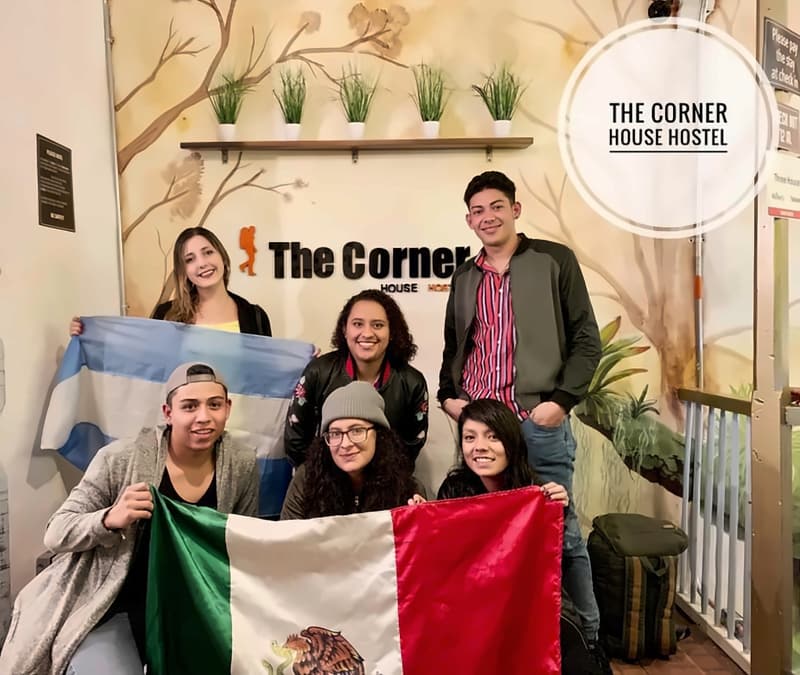 Six young travellers at the reception mural holding the flags of Argentina and Mexico