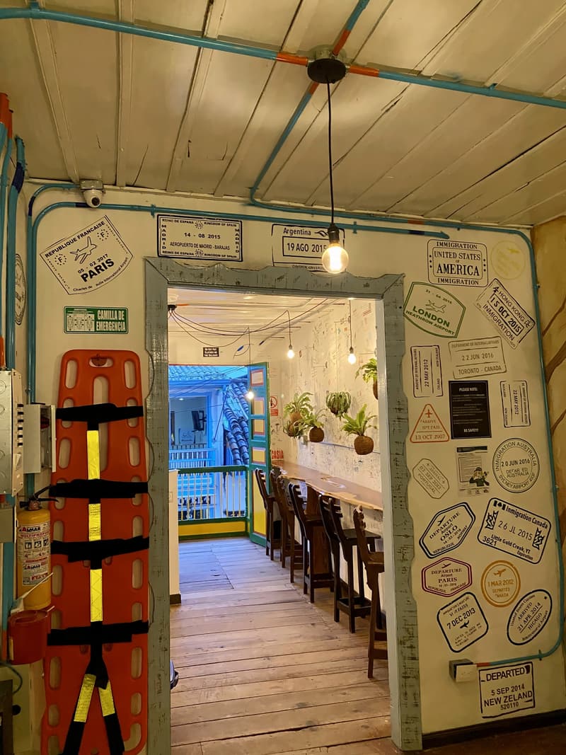An entrance corridor painted with passport-stamp artwork, leading to counter seating by the windows